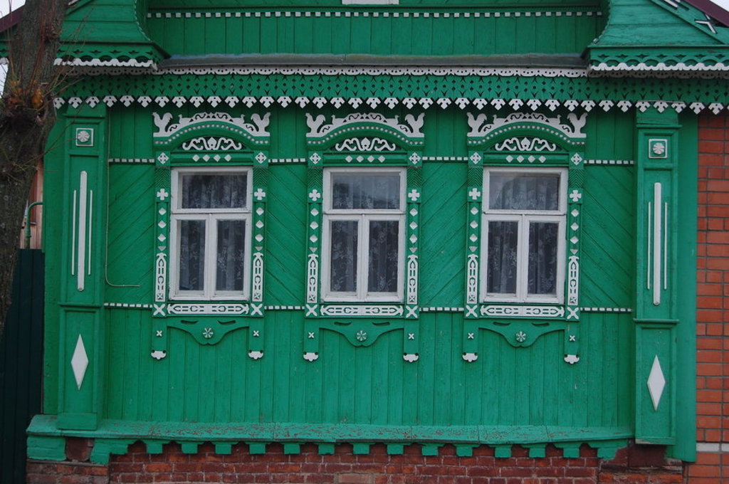 Groene houten gevel met sierlijke witte raamkozijnen, typisch voor Rusland tijdens een groepsrondreis.