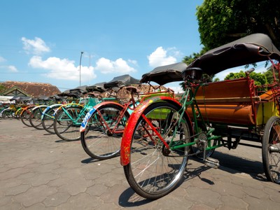 Rij kleurrijke becaks (fietstaxi’s) klaar voor een stadsrit tijdens de Route Java en Bali.