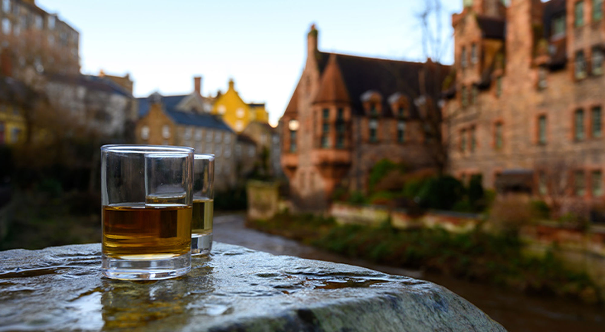 Schotse whisky Twee glazen bier op een stenen rand met historische gebouwen op de achtergrond in Brugge.