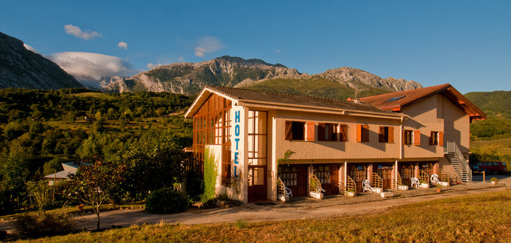 Hotel in de Picos de Europa, Spanje, met uitzicht op groene heuvels en bergtoppen.