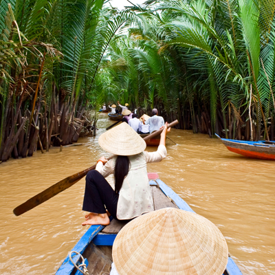 Boottocht door smalle waterwegen tussen palmen tijdens de dagtocht Mekong Delta in Vietnam.