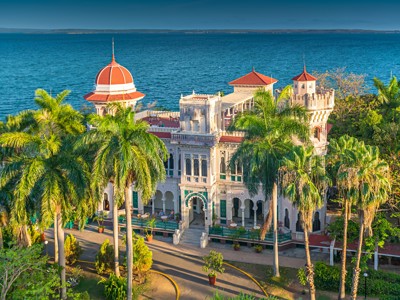 Palacio de Valle in Cienfuegos aan zee, omringd door palmbomen.