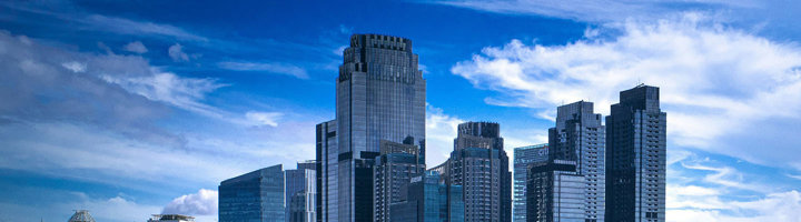Skyline van Jakarta met moderne wolkenkrabbers onder een blauwe lucht.