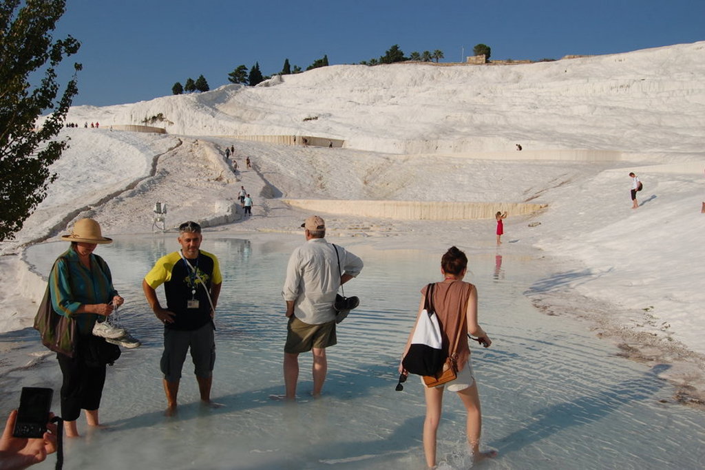 Bezoekers waden door het warme water van de kalkterrassen van Pamukkale tijdens een groepsrondreis Turkije.