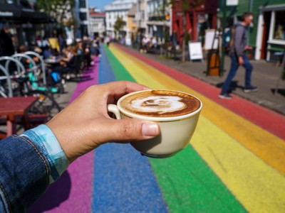 Kop cappuccino in de hand op de regenboogstraat in Reykjavík, IJsland.