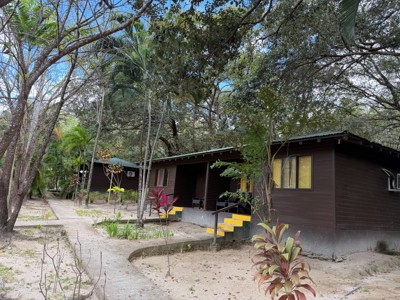Houten bungalow bij Cañon de la Vieja Lodge in Costa Rica, omringd door tropische bomen.