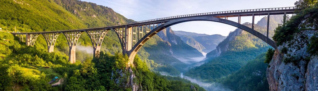 Boogbrug over de Tara-kloof in Montenegro, met beboste bergen en mist in de vallei.