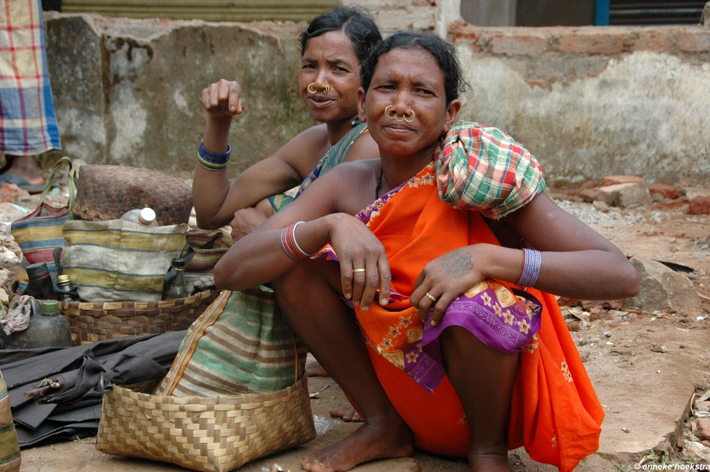 Vrouwen in kleurrijke sari’s op een markt in Orissa, India, met manden en traditionele neusringen.