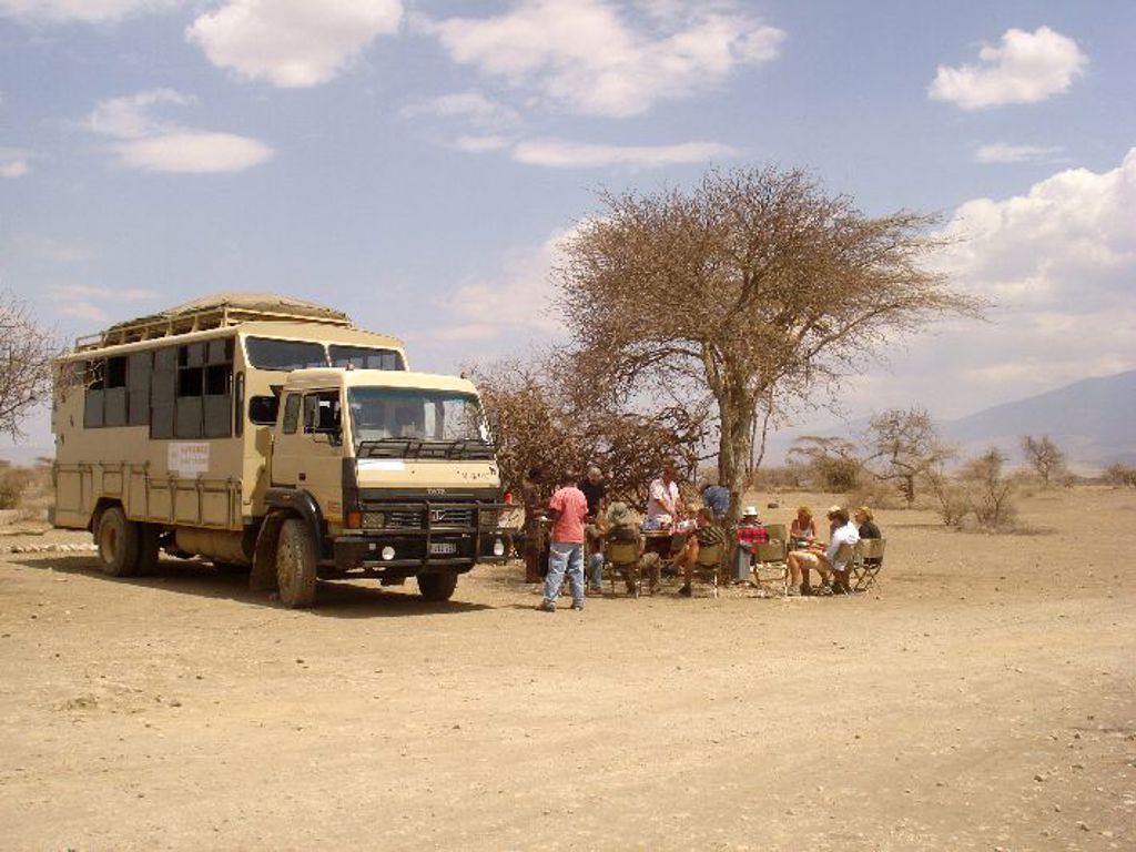 Safari truck met reizigers tijdens picknick in de savanne van Kenia, Tanzania en Zanzibar familiereis.