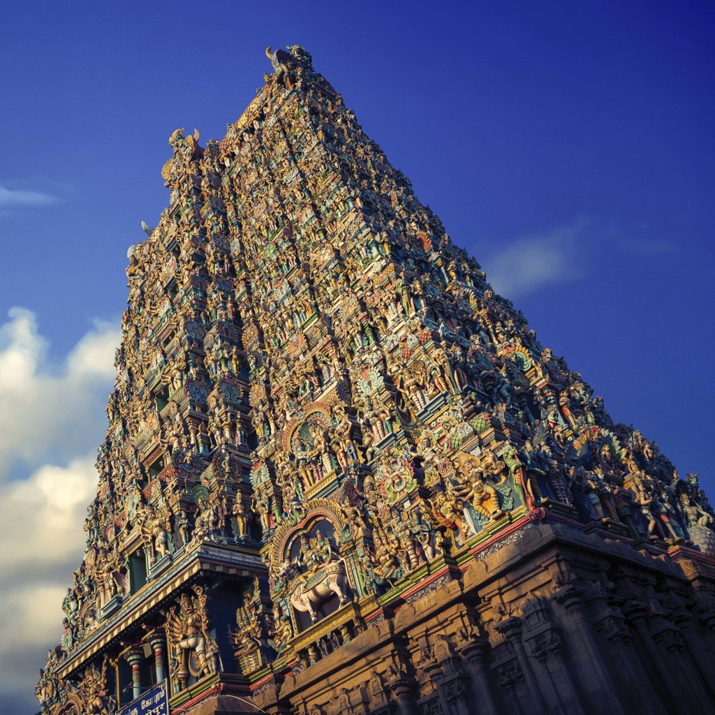 Kleurige hindoetempel in Zuid-India met rijk versierde toren tegen een blauwe lucht.