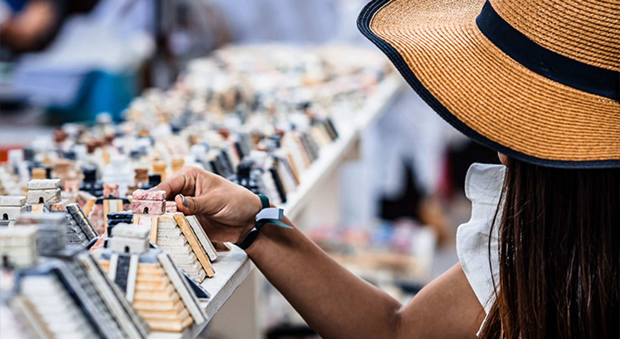 Duurzame souvenirs Vrouw met strohoed bekijkt souvenirs op een markt.