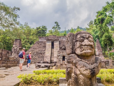 Tempelcomplex Candi Sukuh op Java met stenen wachtersbeeld en bezoekers, route Java en Bali.