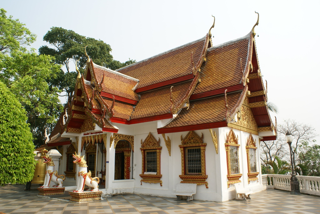 Thaise tempel met rood-gouden dak en wachtersbeelden, een hoogtepunt van de groepsrondreis Thailand Avontuur.