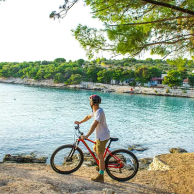 Fietser met mountainbike langs de Kroatische kust met uitzicht op een baai tijdens fietsvakantie Balkan.