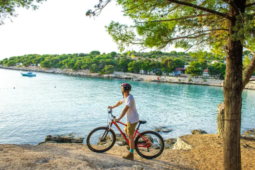 Fietser met mountainbike langs de Kroatische kust met uitzicht op een baai tijdens fietsvakantie Balkan.