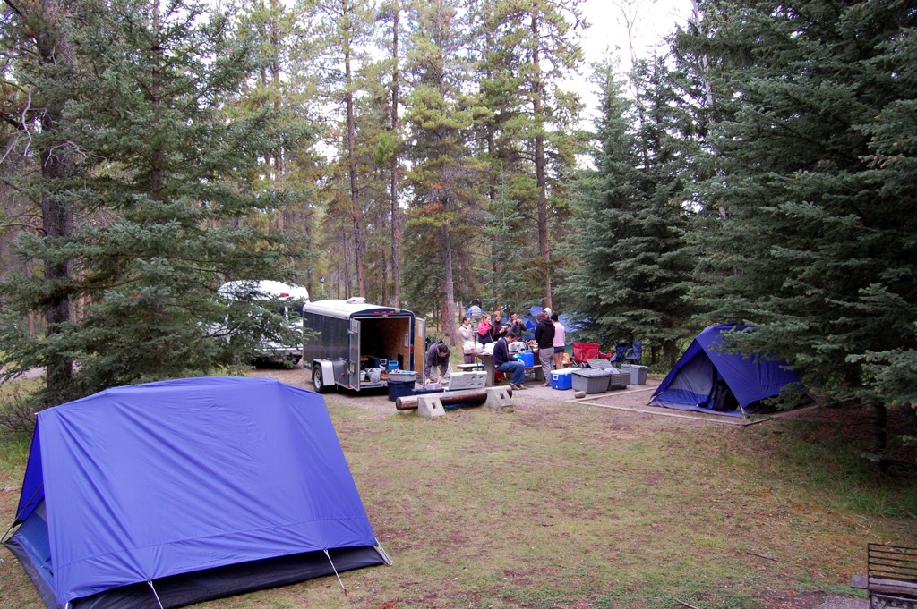 Kampeerplek met tenten en groep reizigers in het bos tijdens familiereis Canada West in de Rockies.
