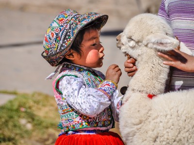 Kind in traditionele kleding met alpaca tijdens Route Peru.