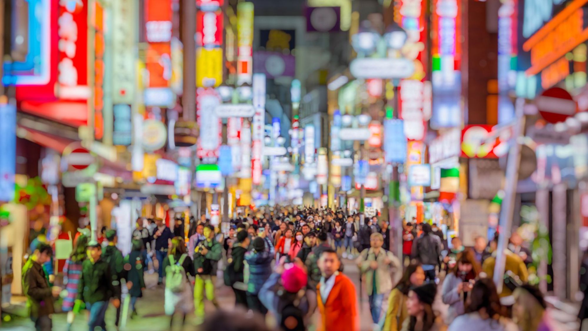 Drukke straat met neonreclames en voetgangers in Tokio, Japan, bij avond.