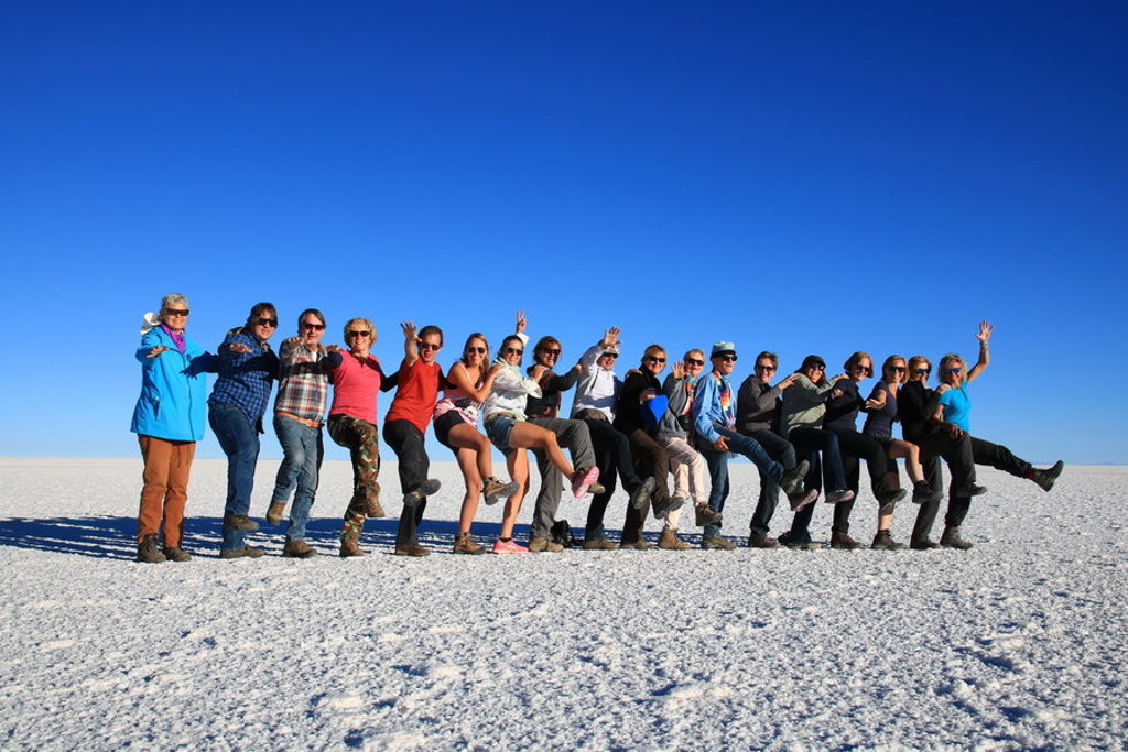 Groep reizigers poseert op de zoutvlakte Salar de Uyuni tijdens een groepsrondreis Bolivia en Chili.
