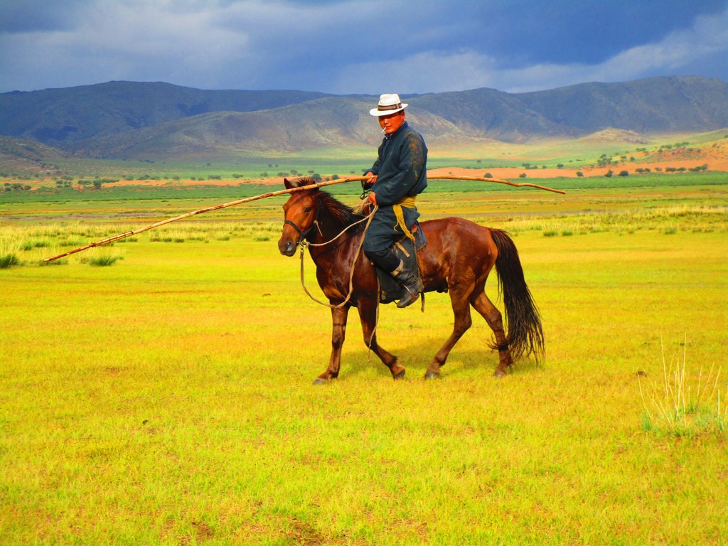 Paardenruiter in de Mongoolse steppe met bergen op de achtergrond tijdens rondreis Trans-Siberië Expres.