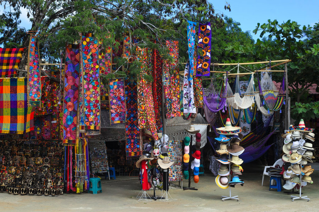 Kleurrijke markt in Mexico met geborduurde doeken, hangmatten en sombrero’s tijdens een 22-35ers reis.