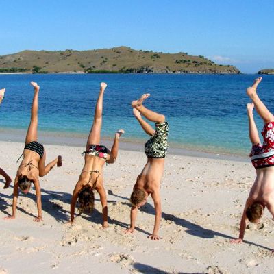 Kinderen doen handstanden op het strand bij de Kleine Sunda Eilanden in Indonesië.