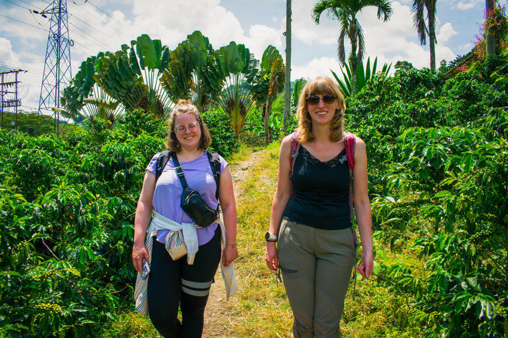 Twee reizigers wandelen door een groene koffieplantage tijdens een 22-35ers reis door Colombia.