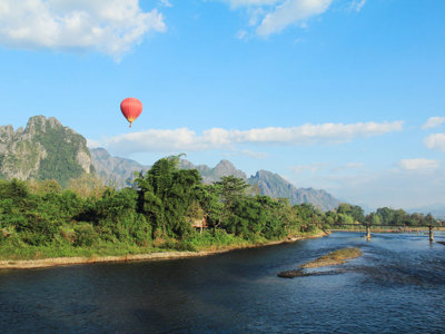 Het landschap van Vang Vieng in Laos met rivier, kalksteenbergen en een luchtballon tijdens de Route Indochina.