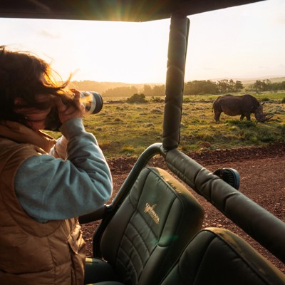 Reiziger spot een neushoorn tijdens safari in Zuid-Afrika bij zonsondergang.
