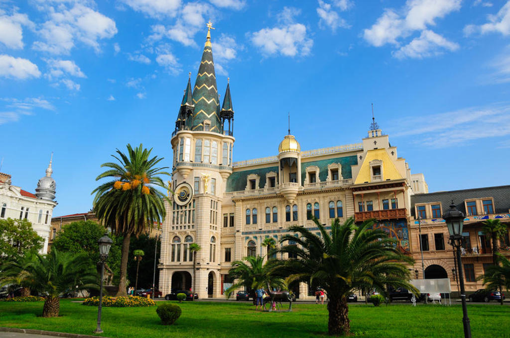 Plein met palmboom en de Astronomische Kloktoren in Batumi, Georgië.