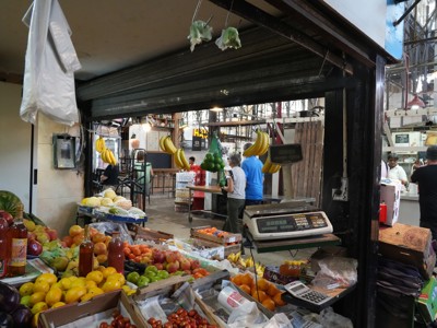 Groente- en fruitkraam in een markthal in Argentinië, met bananen en citrusvruchten aan de toonbank.