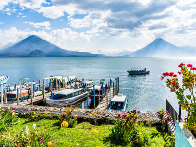 Bootjes bij de aanlegsteiger aan het Meer van Atitlán met vulkanen op de achtergrond, Guatemala.