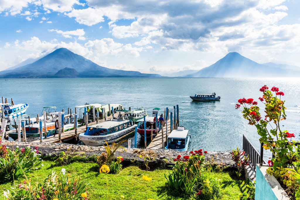 Bootjes bij de aanlegsteiger aan het Meer van Atitlán met vulkanen op de achtergrond, Guatemala.