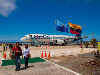 Aankomst op de Galapagoseilanden: reizigers lopen over het vliegveld langs een AeroGal-vliegtuig en Ecuador-vlaggen.