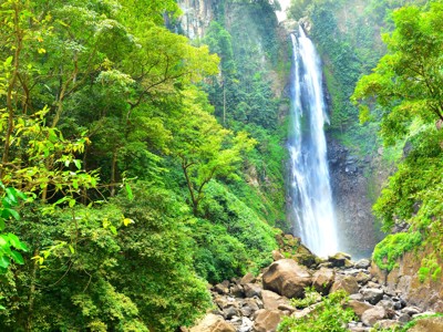 Hoge waterval in een groene junglevallei met rotsen en helder water, Kalimantan, Sulawesi & Molukken.