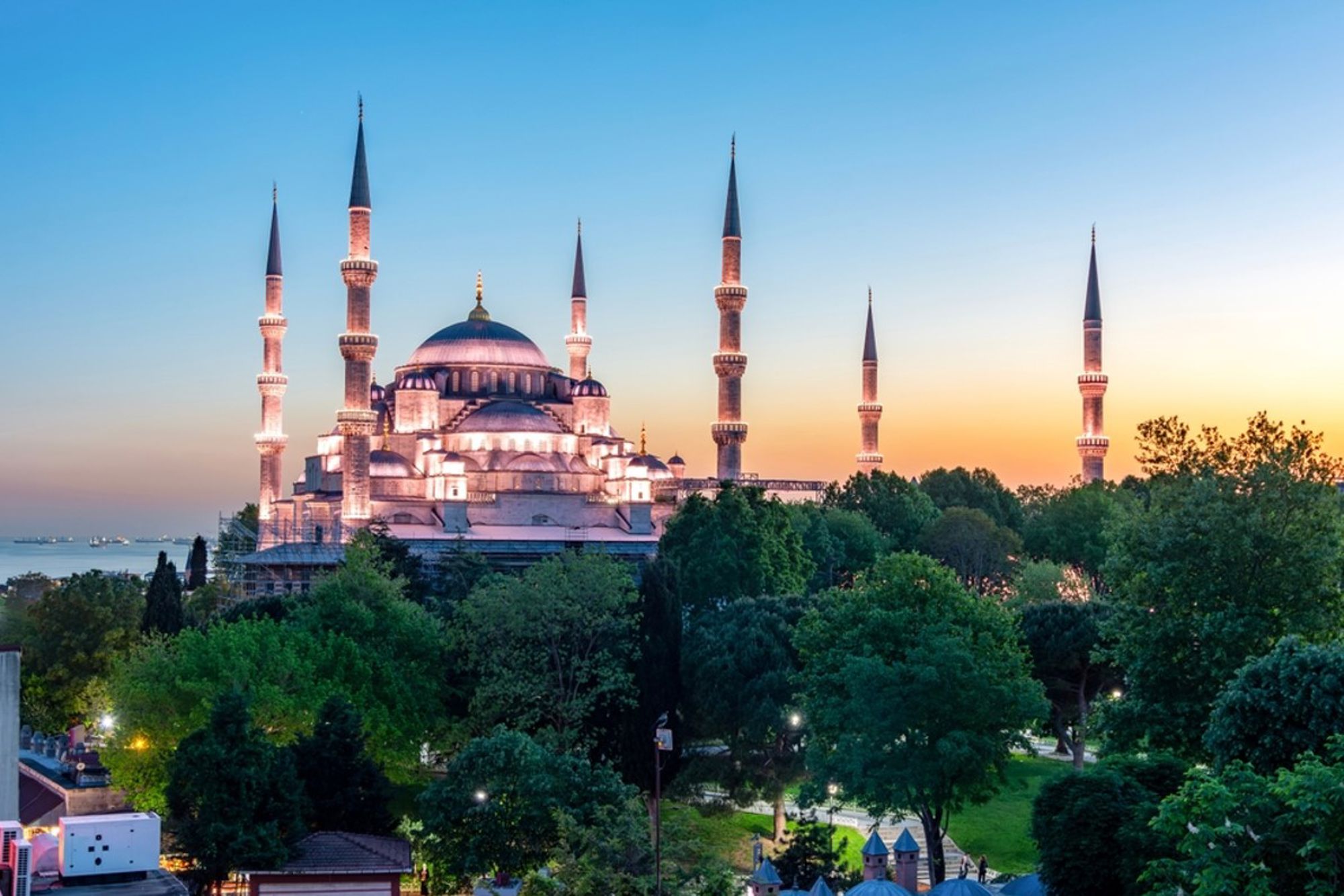 Blauwe Moskee in Istanbul bij zonsondergang, met zes minaretten boven het groen.