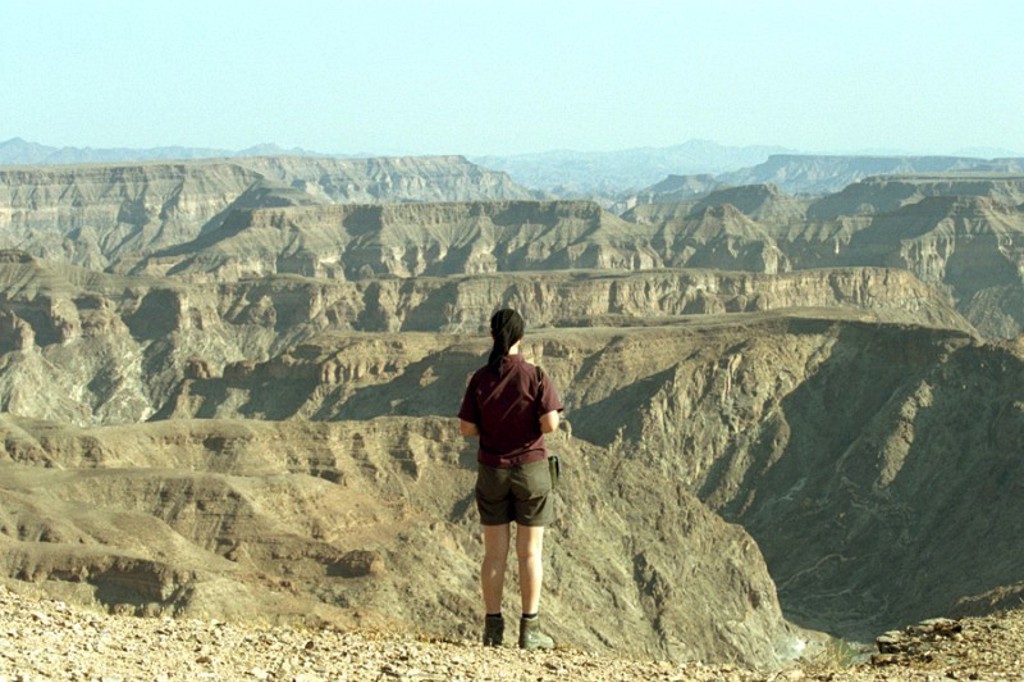 Reiziger kijkt uit over de Fish River Canyon in Namibië tijdens een kampeer-groepsrondreis door Zuidelijk Afrika.