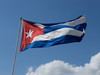 Cubaanse vlag wappert in de wind tegen een blauwe lucht met wolken.