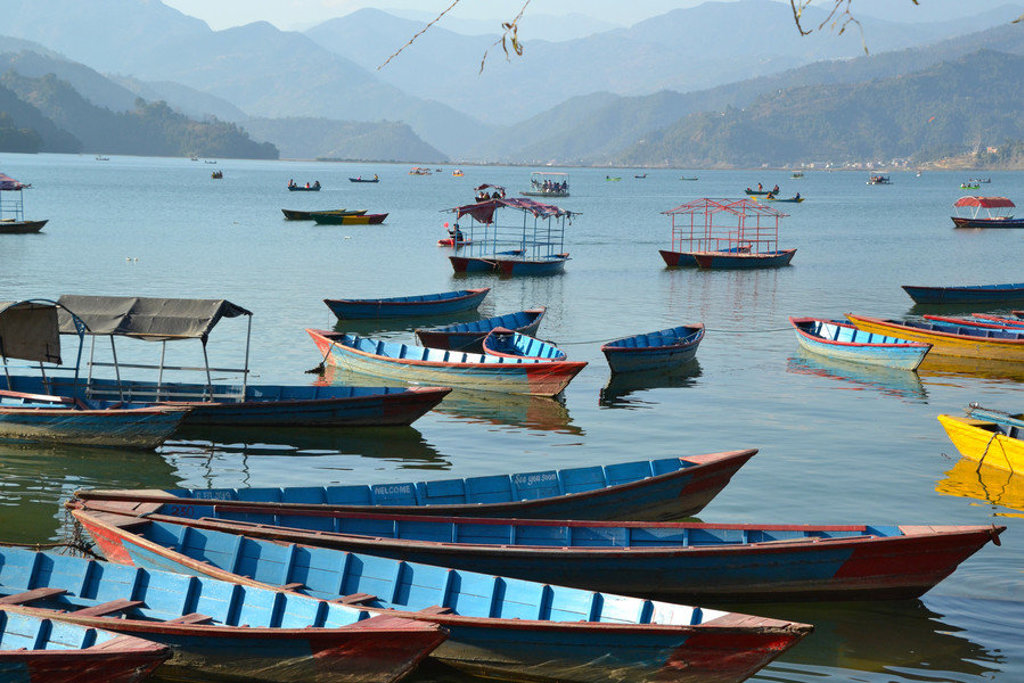 Kleurrijke boten op Phewa Lake bij Pokhara, met bergen op de achtergrond tijdens een 22-35ers reis Nepal.