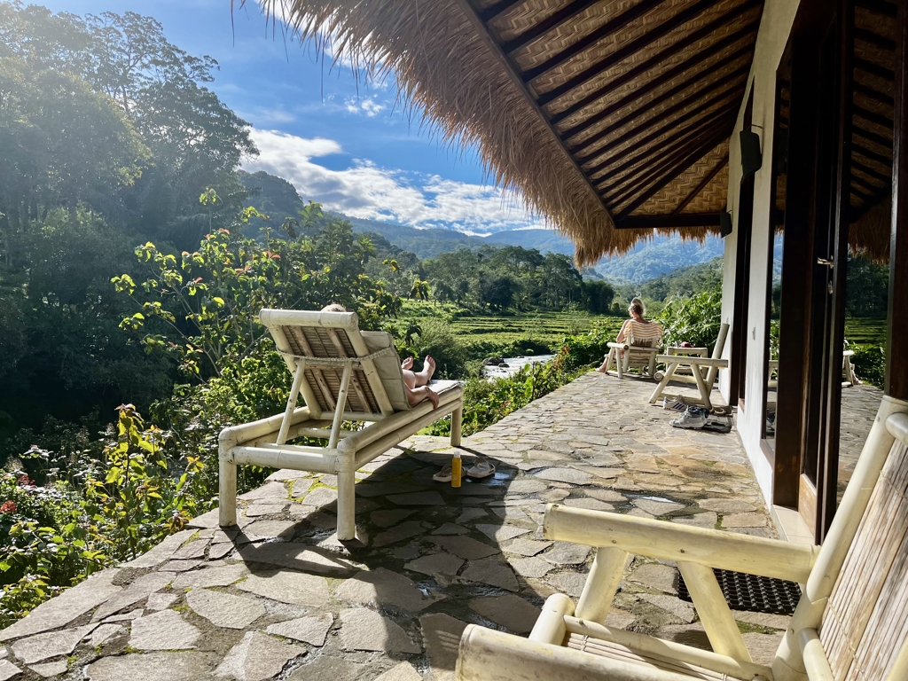 Relaxen op veranda van lodge met uitzicht op groene vallei en bergen op de Kleine Sunda Eilanden, Indonesië.