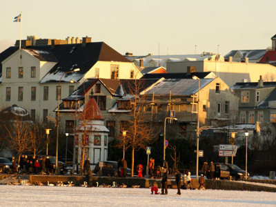 Reykjavik in winterlicht met kleurrijke huizen en mensen langs de besneeuwde waterkant.