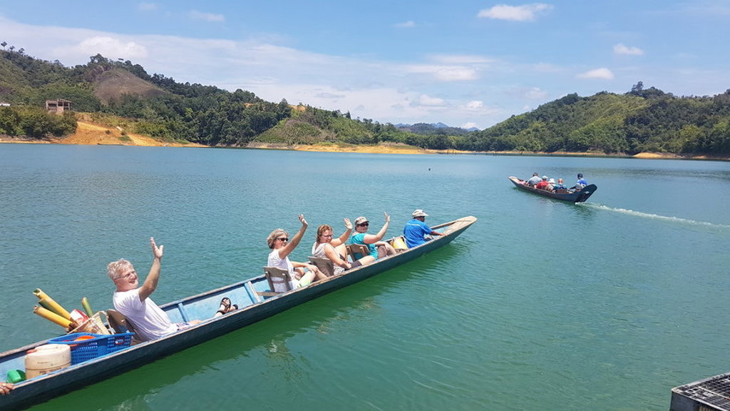 Groepsrondreis Maleisisch Borneo: reizigers in longboat op een meer, met groene heuvels op de achtergrond.