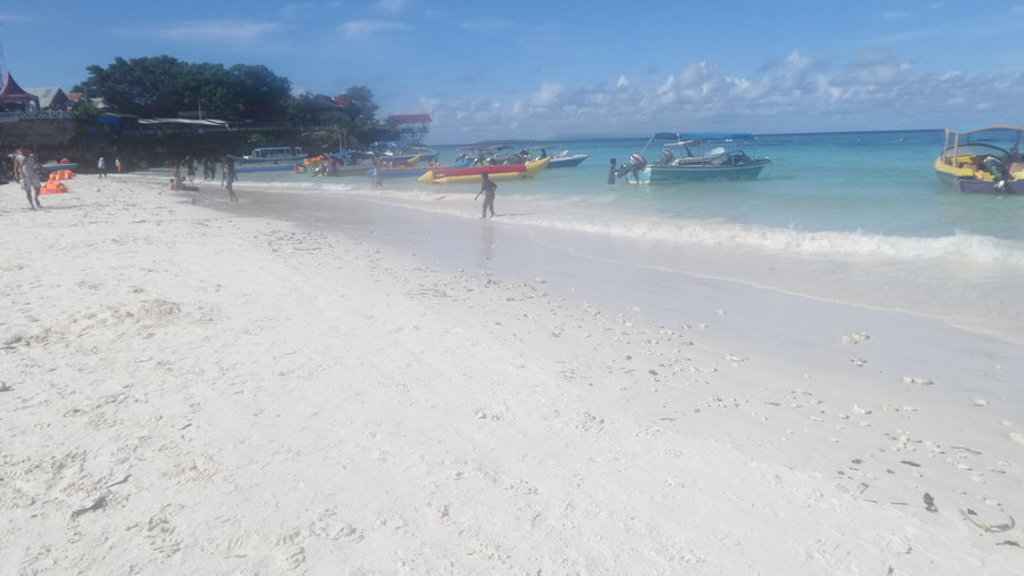 Wit zandstrand met turquoise zee en bootjes bij Kalimantan, Sulawesi en de Molukken.