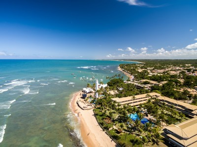 Kustlijn van Praia do Forte in Brazilië met palmbomen, strand en helderblauwe zee.