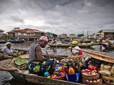 Drijvende markt met vrouwen in kano’s vol groenten en koopwaar op het water in Ghana, Togo en Benin.