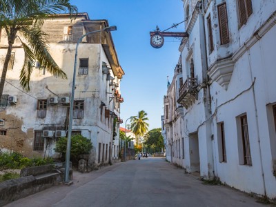 Straat in Stone Town, Zanzibar, met oude koloniale gebouwen en een hangende klok aan de gevel.