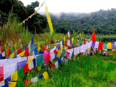 Gekleurde gebedsvlaggen langs een groen bergmeer in Sikkim en Bhutan.