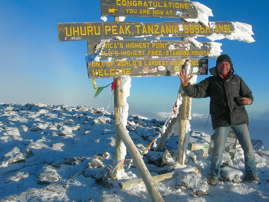 Wandelaar bij het Uhuru Peak-bord op de besneeuwde top van de Kilimanjaro in Tanzania.