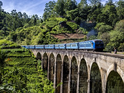 Blauwe trein over de Nine Arch Bridge tussen theeplantages in de heuvels van Sri Lanka.