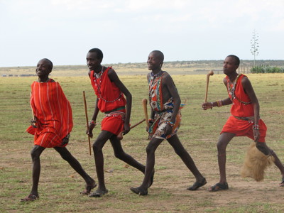 Masai-krijgers in kleurrijke kleding lopen over de savanne in Kenia of Tanzania.